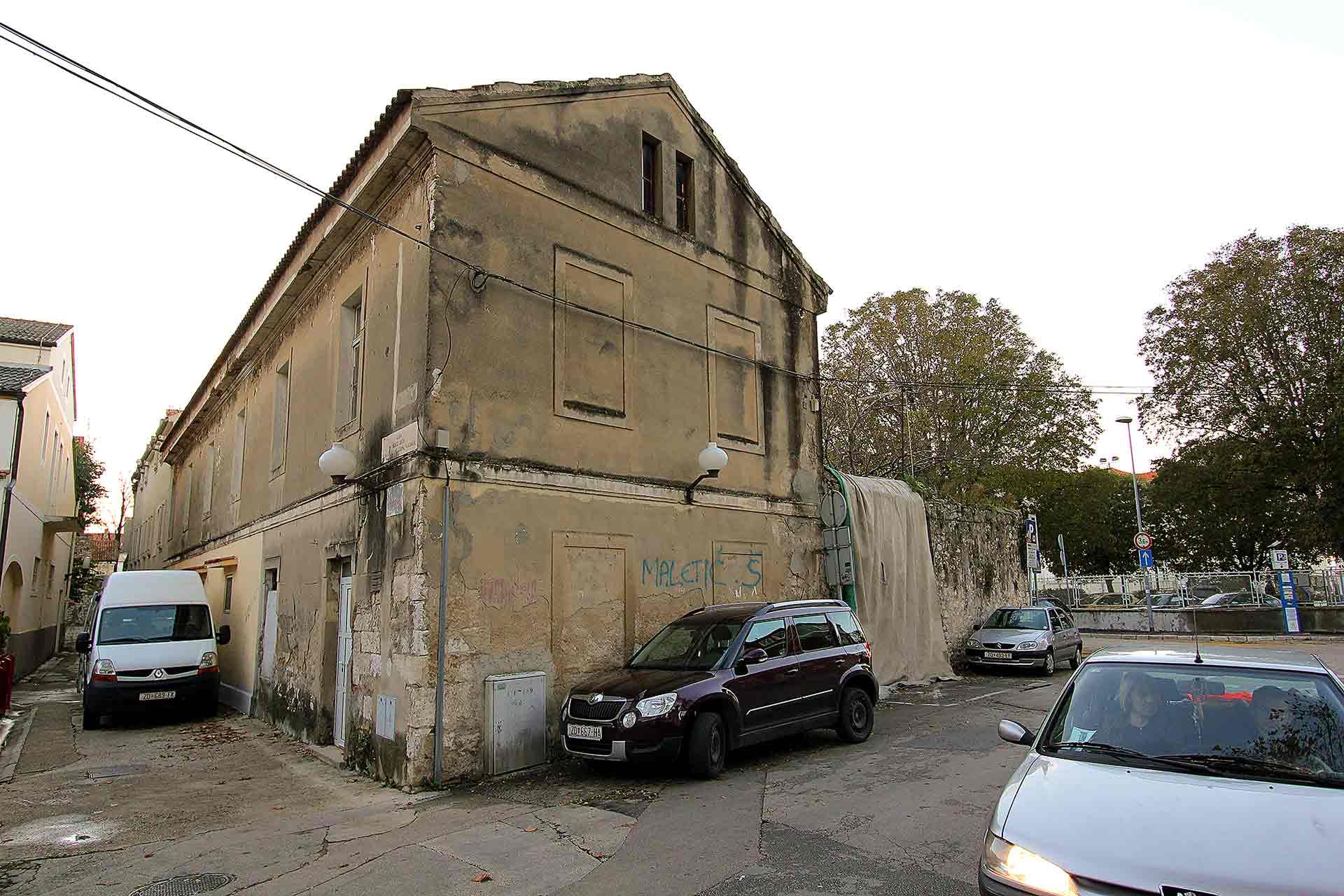Witness the forgotten beauty of the future Almayer Art & Heritage Hotel in Zadar, Croatia, an abandoned building with a car parked in front - a hauntingly intriguing sight.