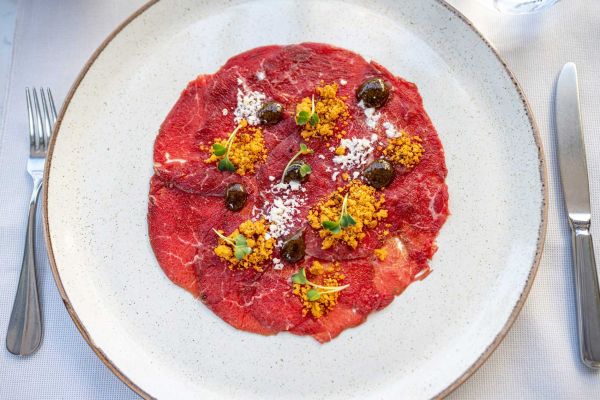 Indulge in exquisite starters, including beef carpaccio, at Corte Restaurant, Almayer Art & Heritage Hotel