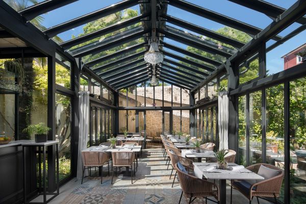 Discover the luminous ambience of Corte Restaurant in Almayer Art & Heritage Hotel's steel and glass Orangerie, surrounded by a verdant secret garden