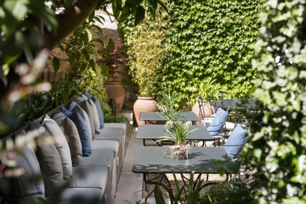 Indulge in the charming ambience of Almayer's patio, nestled within medieval walls, adorned with citrus trees, and overlooking the secret garden